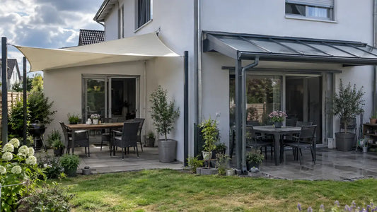 Bewohnte Terrasse mit Sonnensegel neben einer festen transparenten Terrassenüberdachung an einem Einfamilienhaus